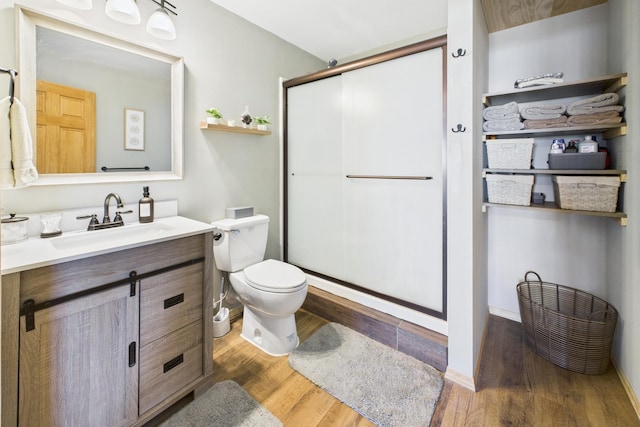 full bathroom with wood finished floors, a shower stall, vanity, and toilet