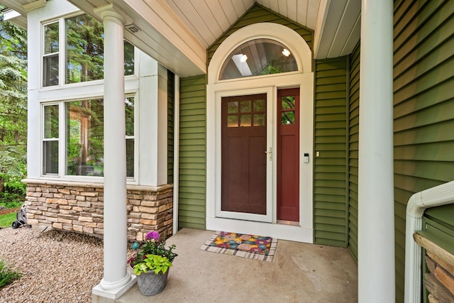 view of exterior entry featuring covered porch and stone siding