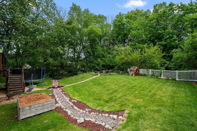 view of yard featuring a trampoline, stairway, and a deck