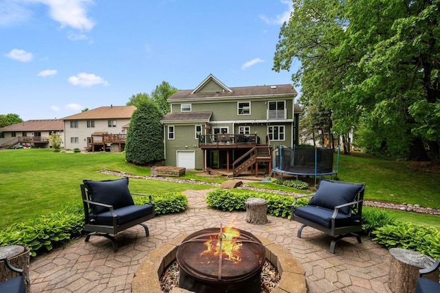 view of patio with an outdoor fire pit, a wooden deck, stairway, and a trampoline