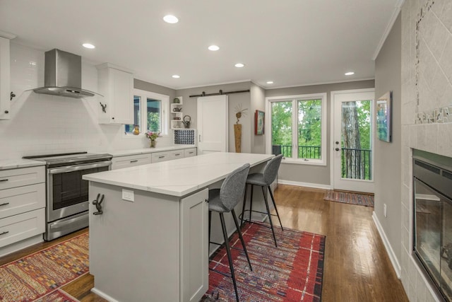 2 Edgcumbe Pl, Saint Paul, MN 55116 - kitchen with stainless steel electric range, wall chimney exhaust hood, a center island, a kitchen bar, and white cabinets