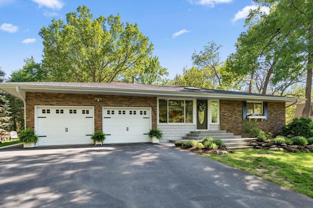view of front of house with a garage, asphalt driveway, brick siding, and entry steps