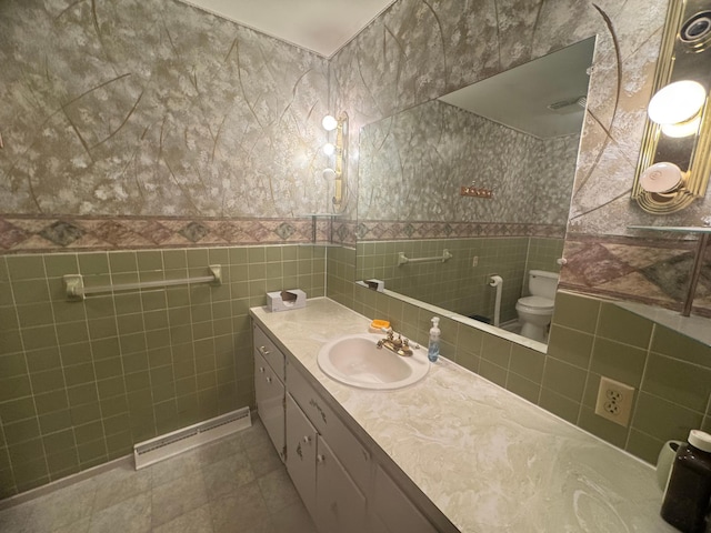 1725 Woodlawn Ave, Owatonna, MN 55060 - bathroom featuring tile walls, toilet, vanity, and a baseboard radiator
