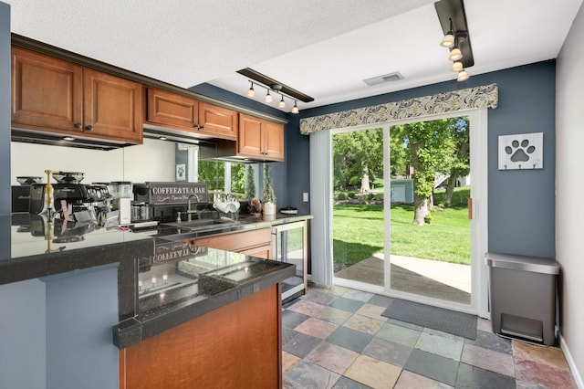 12037 Robin Rd, Maple Grove, MN 55369 - kitchen featuring beverage cooler, a sink, track lighting, dark countertops, and brown cabinetry