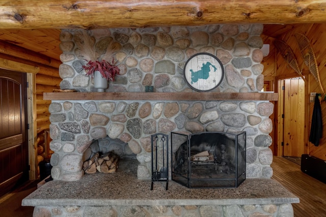 detailed view of a stone fireplace, log walls, wood finished floors, and wood ceiling