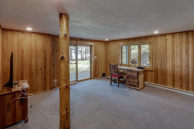 carpeted office space with a textured ceiling, wood walls, baseboard heating, and recessed lighting