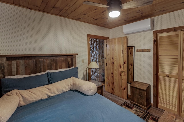 bedroom with a wall unit AC, wallpapered walls, a closet, a ceiling fan, and wooden ceiling