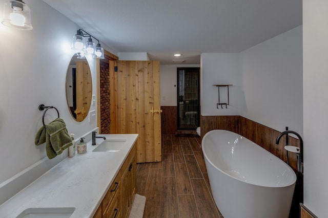 full bath with wood tiled floors, a freestanding bath, double vanity, a stall shower, and recessed lighting