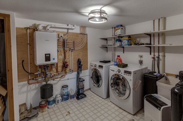 washroom with water heater, separate washer and dryer, light flooring, and a textured ceiling