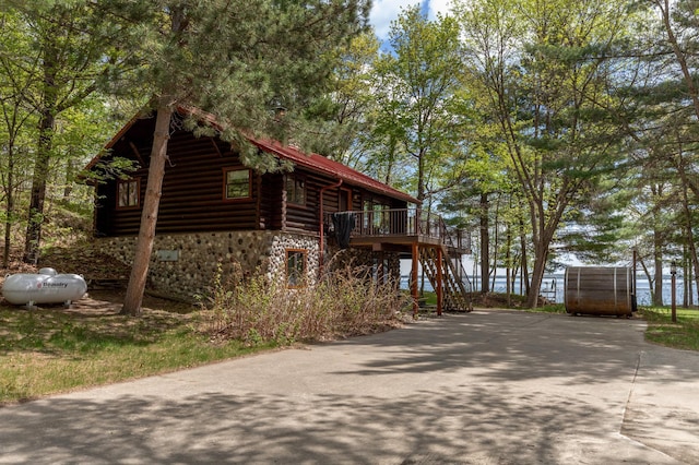 view of side of property with stairs, stone siding, a wooden deck, and log exterior