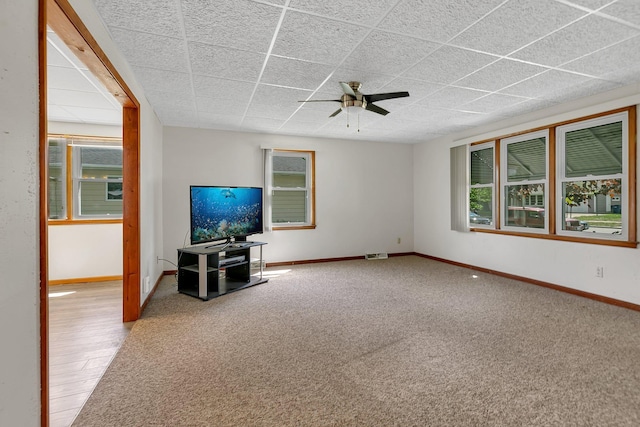 unfurnished living room with a ceiling fan, baseboards, a paneled ceiling, and carpet floors