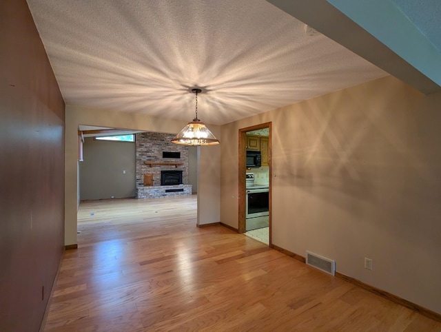 unfurnished dining area featuring a large fireplace, light wood-style floors, and baseboards