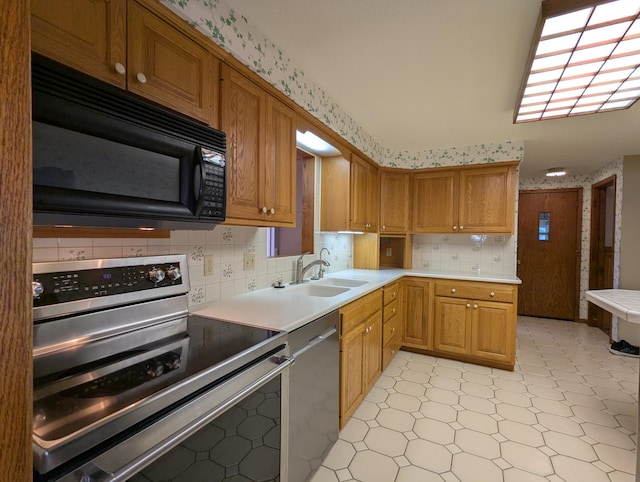 kitchen with appliances with stainless steel finishes, a sink, light flooring, light countertops, and decorative backsplash