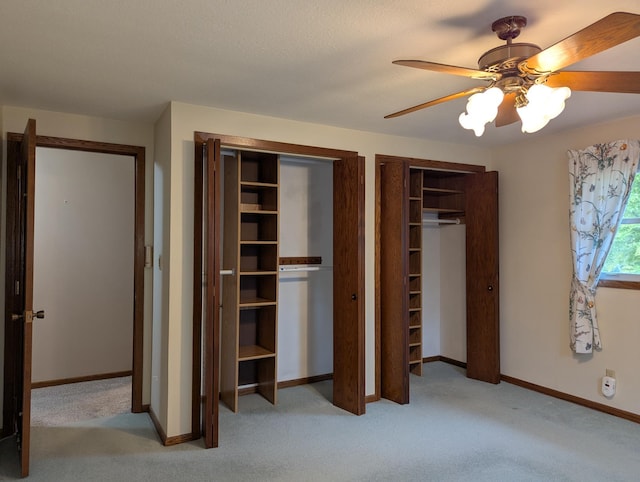 unfurnished bedroom featuring multiple closets, carpet, baseboards, and ceiling fan