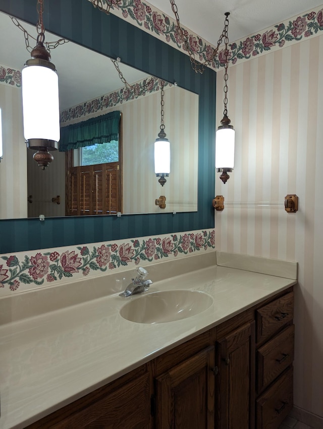 bathroom with wallpapered walls and vanity