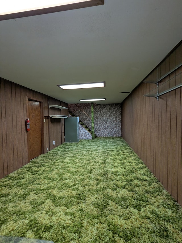 hallway with wooden walls, carpet floors, and stairs