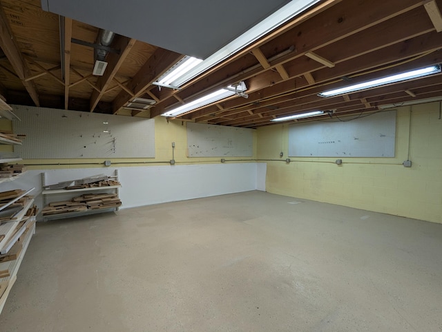 unfinished basement with concrete block wall and a workshop area
