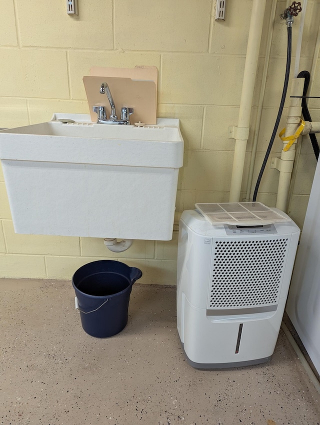 bathroom featuring concrete block wall and a sink