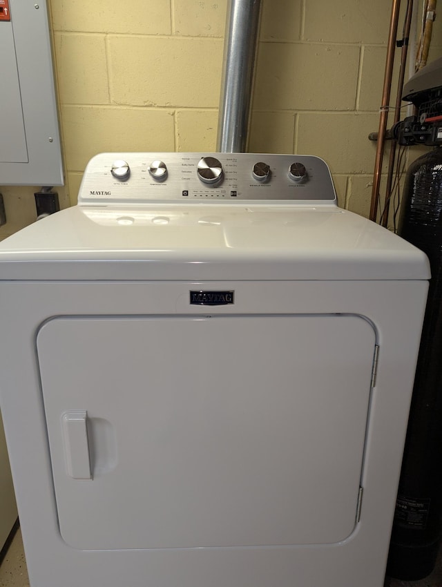clothes washing area with washer / clothes dryer and concrete block wall