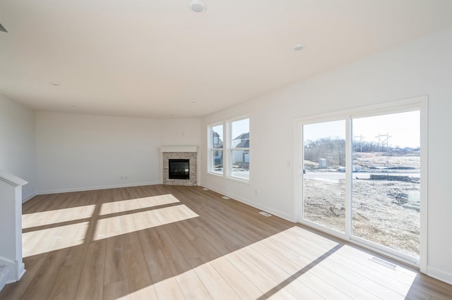 unfurnished living room with wood finished floors, a fireplace, and baseboards