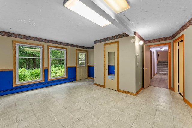 331 Sunset Ln N, Cambridge, MN 55008 - empty room with plenty of natural light, stairs, and baseboard heating