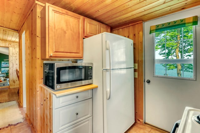 20473 Leisure Dr, Pelican Rapids, MN 56572 - kitchen featuring stainless steel microwave, wooden ceiling, freestanding refrigerator, light tile patterned floors, and light countertops