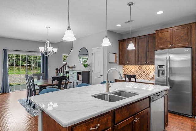 12266 Midway Cir NE, Blaine, MN 55449 - kitchen featuring a sink, appliances with stainless steel finishes, tasteful backsplash, a center island with sink, and a chandelier