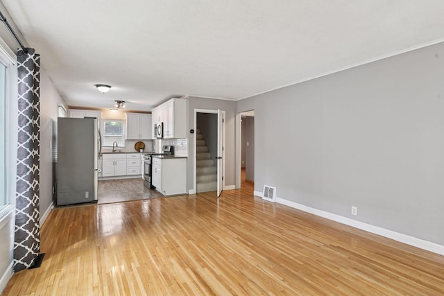 426 14th Ave N, Hopkins, MN 55343 - unfurnished living room with light wood-style flooring, baseboards, a sink, and stairway