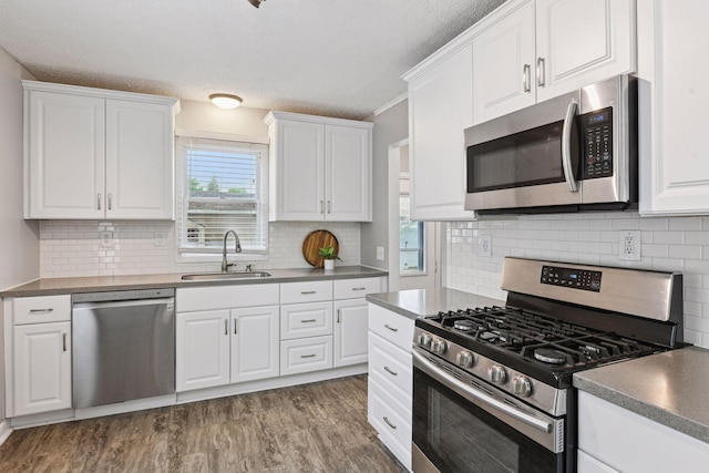 426 14th Ave N, Hopkins, MN 55343 - kitchen with appliances with stainless steel finishes, a sink, a textured ceiling, white cabinetry, and wood finished floors