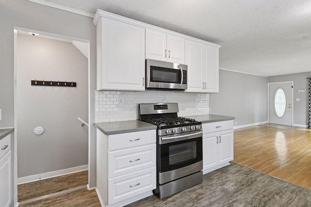 426 14th Ave N, Hopkins, MN 55343 - kitchen with appliances with stainless steel finishes, dark countertops, dark wood-type flooring, tasteful backsplash, and a textured ceiling