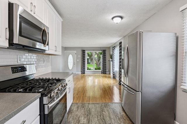 426 14th Ave N, Hopkins, MN 55343 - kitchen with appliances with stainless steel finishes, dark wood finished floors, tasteful backsplash, white cabinetry, and a textured ceiling