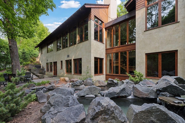 20545 Linden Rd, Deephaven, MN 55331 - rear view of house featuring a small pond, a patio area, and stucco siding