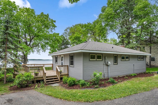 10001 Jeske Ave NW, Corinna Twp, MN 55302 - view of home's exterior featuring a deck with water view, a shingled roof, and a lawn