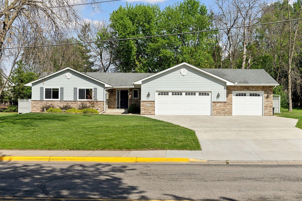1445 Bay Dr SE, Forest Lake, MN 55025 - view of front of home featuring a garage, concrete driveway, stone siding, and a front yard