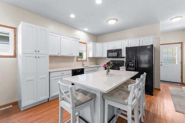2737 Faulkner Dr, Chaska, MN 55318 - kitchen featuring black appliances, a sink, light wood finished floors, a kitchen bar, and recessed lighting