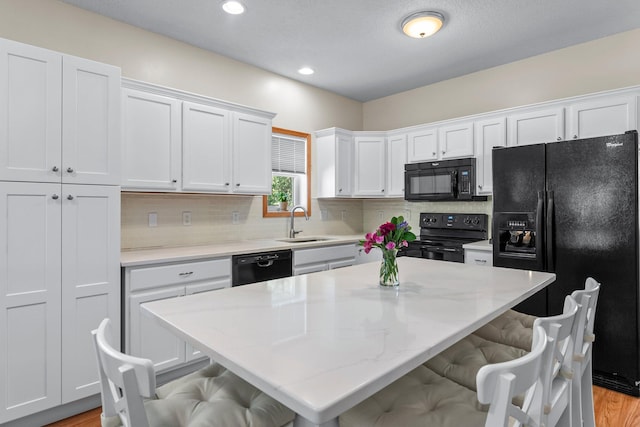 2737 Faulkner Dr, Chaska, MN 55318 - kitchen with black appliances, a sink, white cabinetry, a kitchen breakfast bar, and decorative backsplash