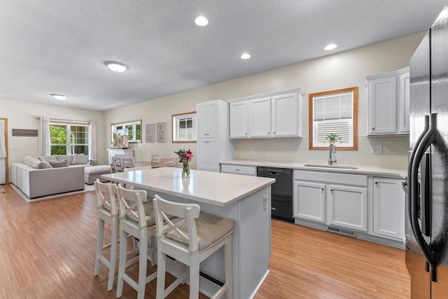 2737 Faulkner Dr, Chaska, MN 55318 - kitchen with black appliances, a sink, a kitchen bar, light countertops, and light wood-type flooring