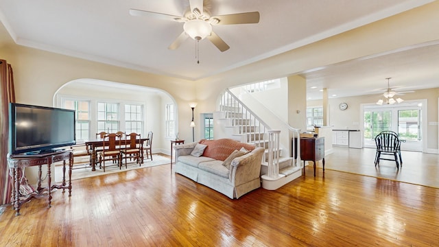 living area featuring ceiling fan, stairway, arched walkways, and light wood-type flooring