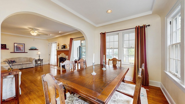 dining room featuring arched walkways, wood finished floors, ceiling fan, recessed lighting, and baseboards