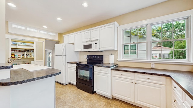 kitchen with white appliances, dark countertops, plenty of natural light, recessed lighting, and white cabinets