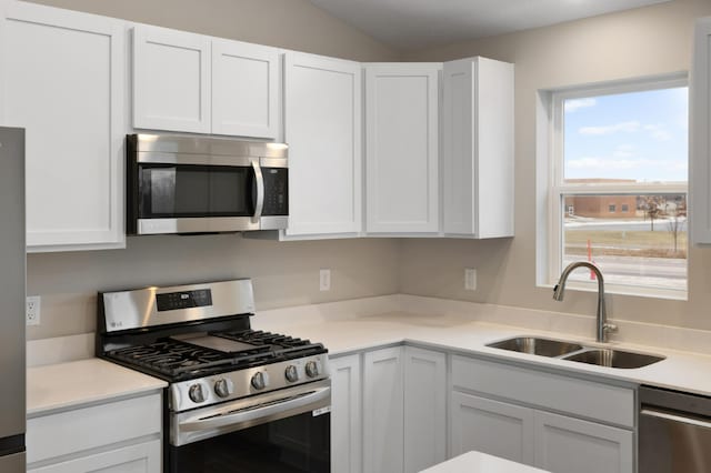7463 147th Ln NW, Ramsey, MN 55303 - kitchen with appliances with stainless steel finishes, a sink, white cabinetry, light countertops, and vaulted ceiling