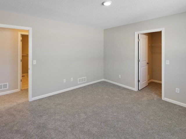 7463 147th Ln NW, Ramsey, MN 55303 - unfurnished bedroom featuring a walk in closet, carpet flooring, baseboards, a closet, and a textured ceiling