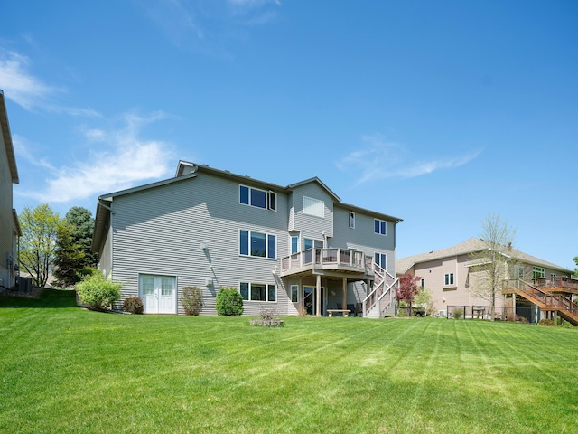 rear view of house with stairway, a wooden deck, and a yard