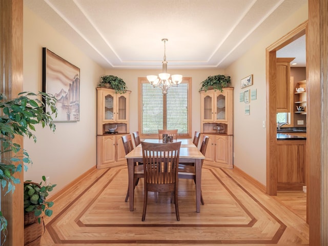 dining area with a chandelier, a tray ceiling, and baseboards