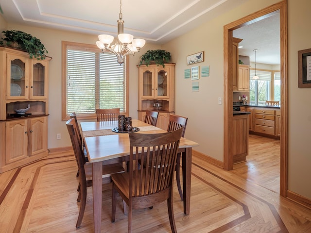 dining space featuring a chandelier, a tray ceiling, and baseboards