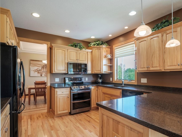 kitchen with black appliances, a sink, dark countertops, light wood finished floors, and pendant lighting