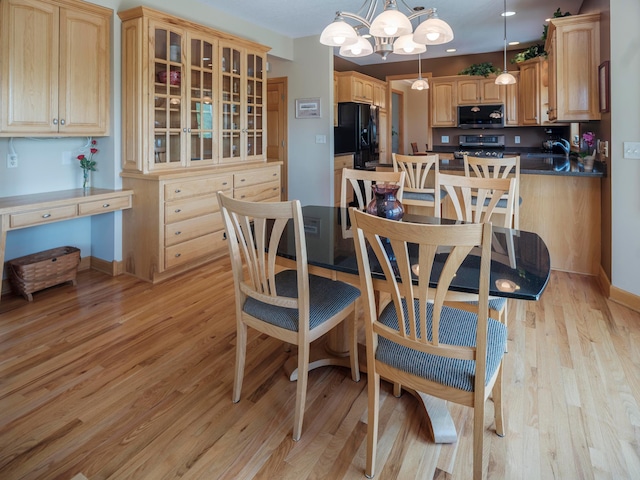 dining room with light wood finished floors, a chandelier, and baseboards