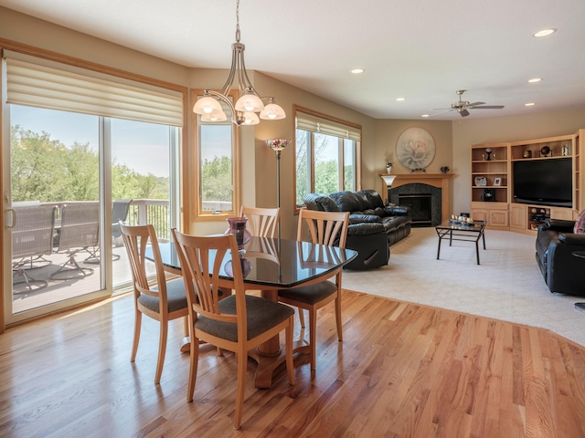 dining room with recessed lighting, ceiling fan, light wood finished floors, a fireplace, and a chandelier