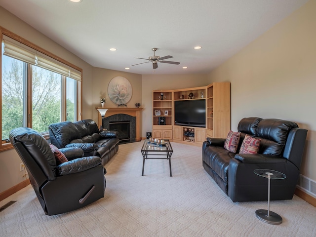 living area with recessed lighting, a ceiling fan, baseboards, a glass covered fireplace, and light colored carpet
