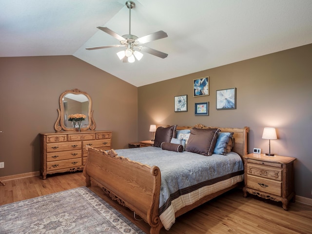 bedroom with wood finished floors, vaulted ceiling, baseboards, and ceiling fan